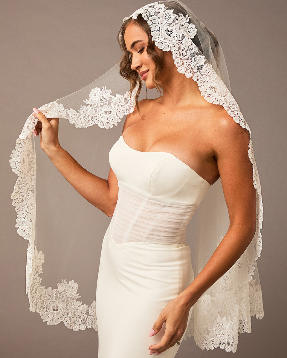 Woman wearing a white wedding dress with a lace veil against a neutral background Mantilla Veil with Wide Flower Chantilly Lace