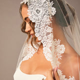 Woman wearing a lace veil with a plain background Mantilla Cathedral Veil with Wide Flower Chantilly Lace