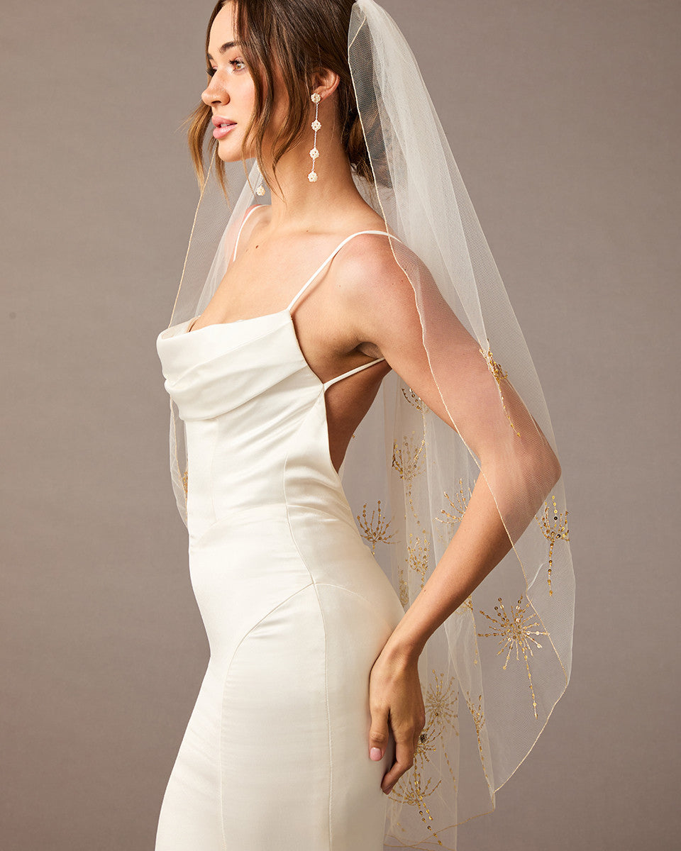 Fingertip Veil with Gold Sequined Dandelion Accents Woman wearing a wedding dress with a sheer veil against a neutral background