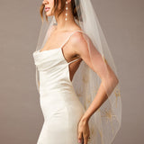 Fingertip Veil with Gold Sequined Dandelion Accents Woman wearing a wedding dress with a sheer veil against a neutral background