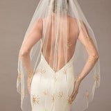 Fingertip Veil with Gold Sequined Dandelion Accents wedding dress with a sheer veil featuring gold embroidery on a plain background