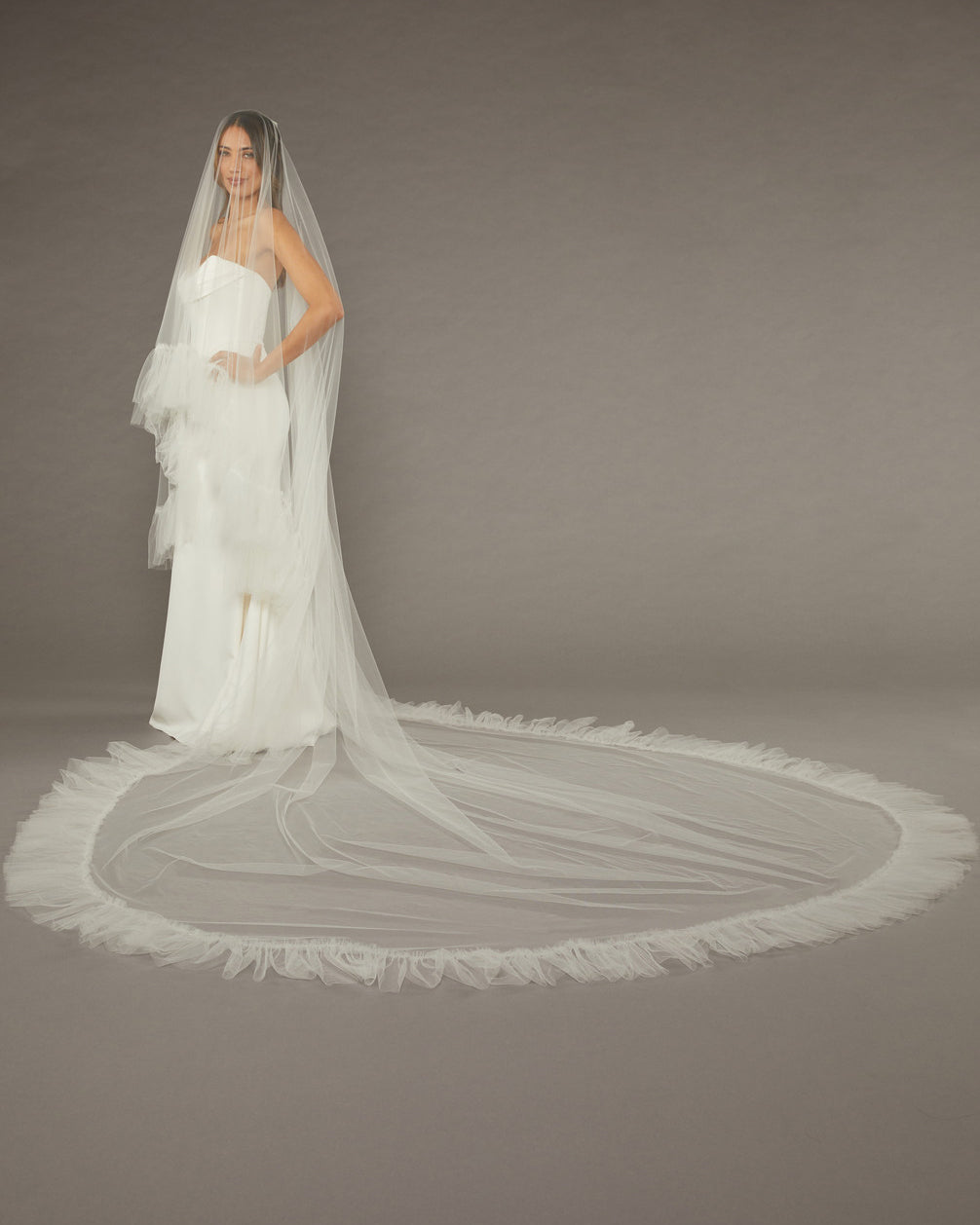 Luxe Tulle Ruffle Edge Two Layer Mantilla Cathedral Bridal Veil Bride in a wedding dress with a long veil on a plain background