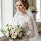 Gold Tiara Comb with Freshwater Pearls A bride in a long-sleeve lace wedding dress and veil holds a bouquet of cream roses and green foliage in a bright indoor setting.