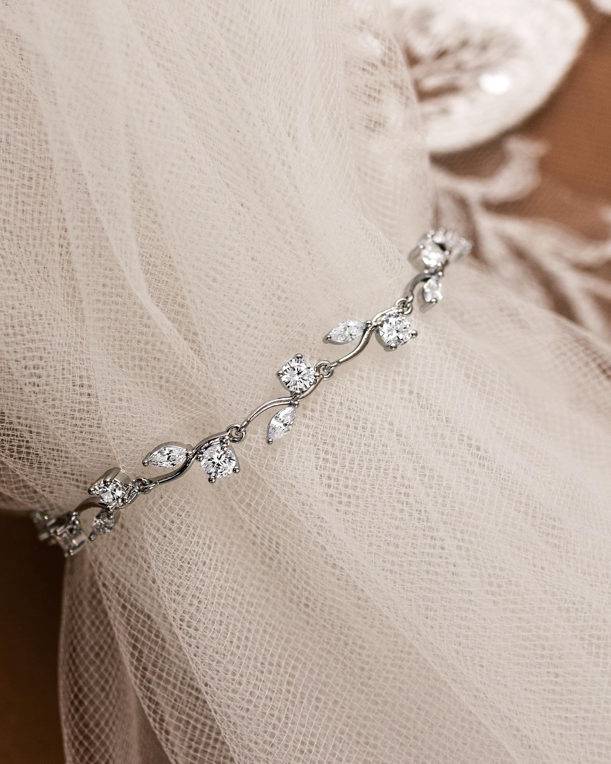 CZ Bracelet Marquise and Round Vine A delicate silver vinebracelet adorned with clear cz, draped over a soft beige tulle fabric.
