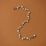 CZ Bracelet Marquise and Round Vine A silver vine bracelet with clear marquise and round-cut stones, arranged in an S-shape on a solid brown background.