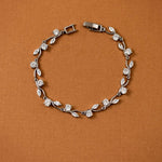 CZ Bracelet Marquise and Round Vine A silver-toned leaf and diamond bracelet arranged in a circle on a textured brown background.