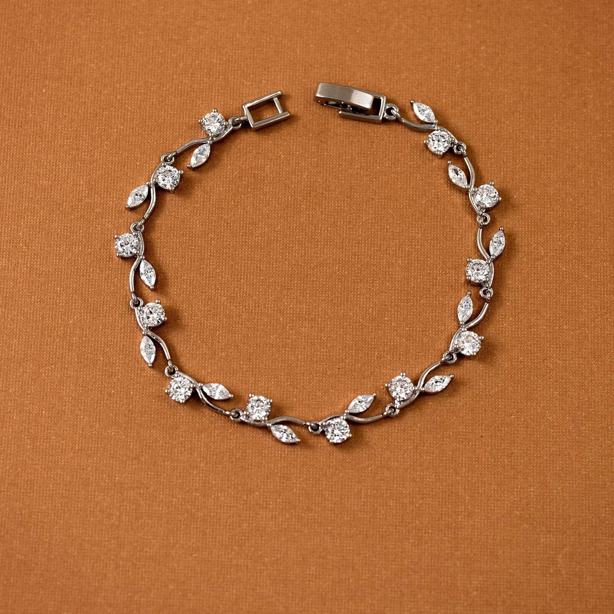 CZ Bracelet Marquise and Round Vine A silver-toned leaf and diamond bracelet arranged in a circle on a textured brown background.
