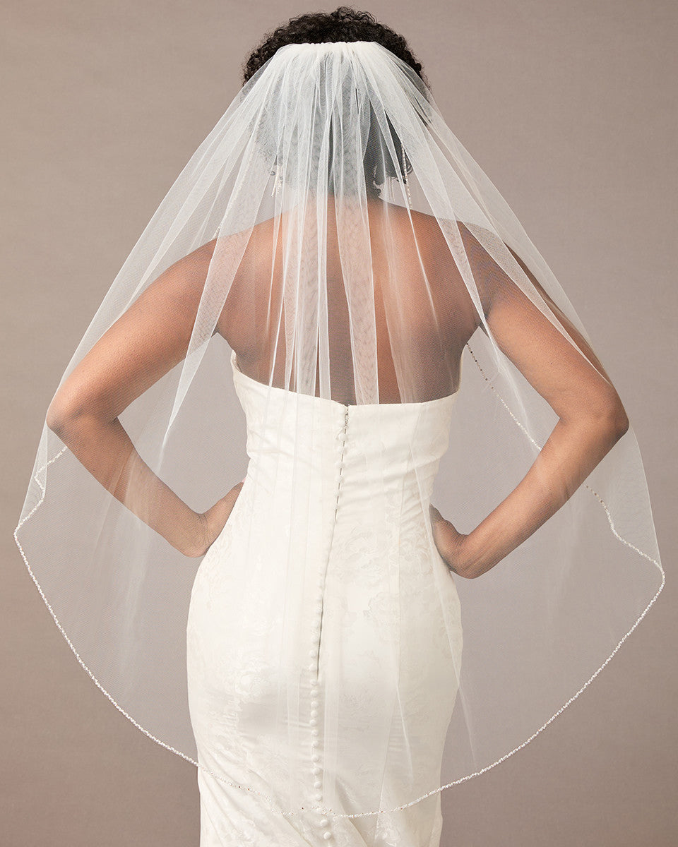 Fingertip Bridal Veil with Iridescent Rhinestones Woman wearing a wedding dress with a sheer veil against a neutral background