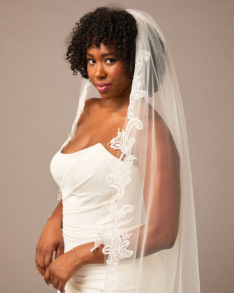 Cathedral Bridal Veil with Venetian Style Lace Woman wearing a wedding dress with a lace veil against a neutral background