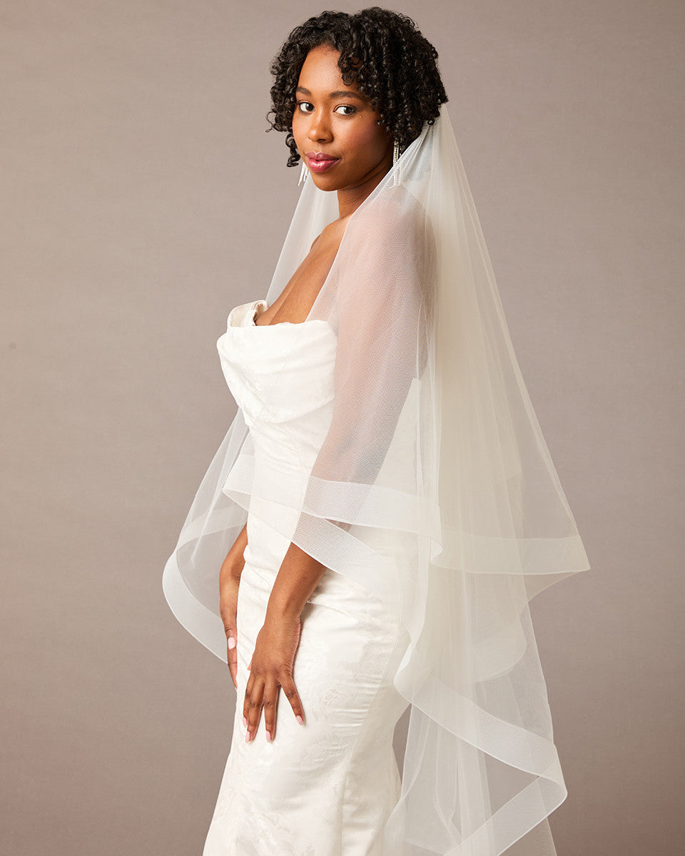 Two Inch Horsehair Trim Waltz Veil Woman wearing a wedding dress with a veil against a plain background
