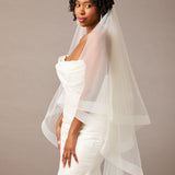 Two Inch Horsehair Trim Waltz Veil Woman wearing a wedding dress with a veil against a plain background