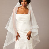 Two Inch Horsehair Trim Waltz Veil Woman wearing awedding dress with a sheer overcoat against a plain background