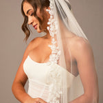 Ivory Luxe Tulle Lace Trim Royal Cathedral Bridal Veil Woman wearing a wedding dress with a lace veil against a neutral background