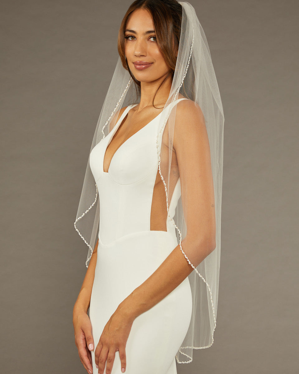 Square Sequins Fingertip Bridal Veil Woman wearing a  wedding dress with a sheer veil against a brown background