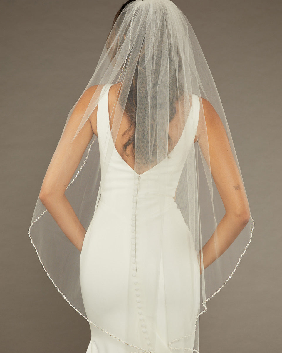 Square Sequins Fingertip Bridal Veil Bride wearing a dress with a sheer veil against a brown background