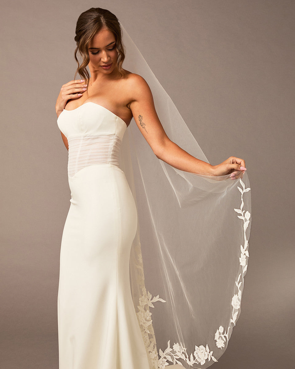 Lace Beaded Waltz Mantilla Wedding Veil Woman wearing a strapless white wedding dress with a floral veil against a plain background
