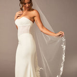 Lace Beaded Waltz Mantilla Wedding Veil Woman wearing a strapless white wedding dress with a floral veil against a plain background