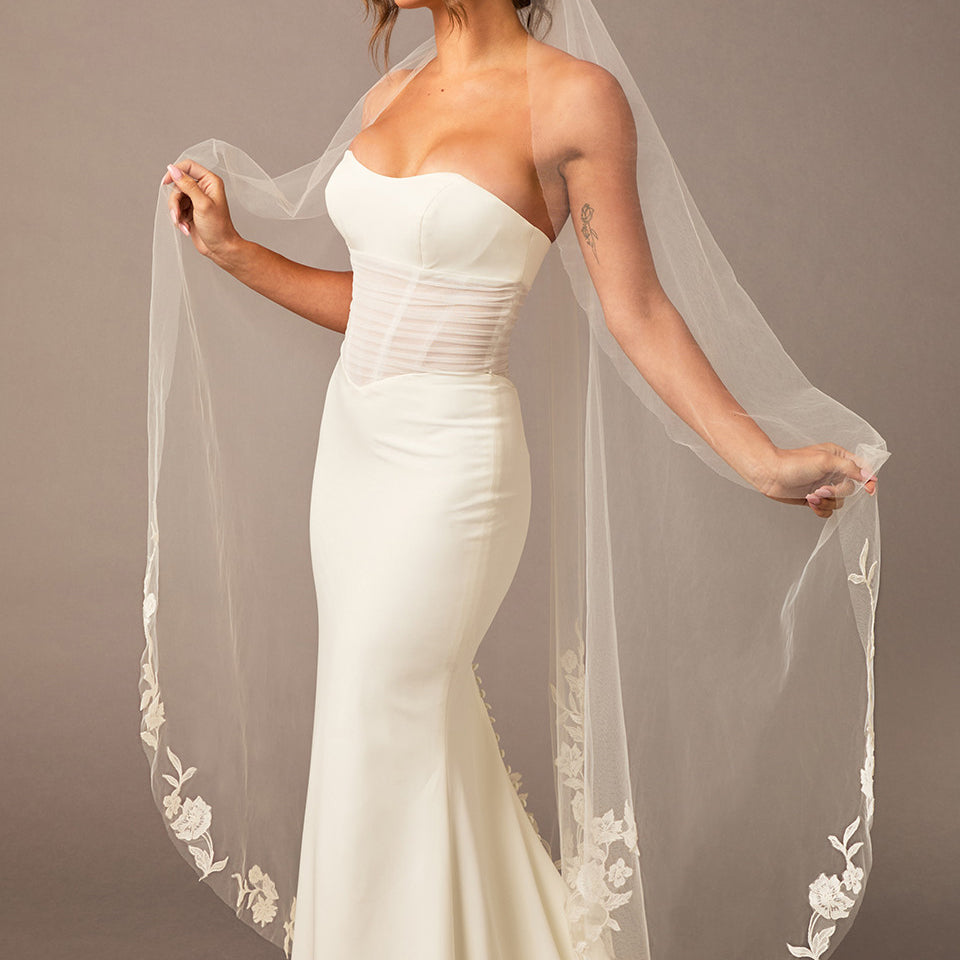  Lace Beaded Waltz Mantilla Wedding Veil Woman wearing a white wedding dress with a long veil against a plain background