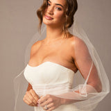  Lace Beaded Waltz Mantilla Wedding Veil Woman wearing a strapless white wedding dress with a sheer veil against a neutral background