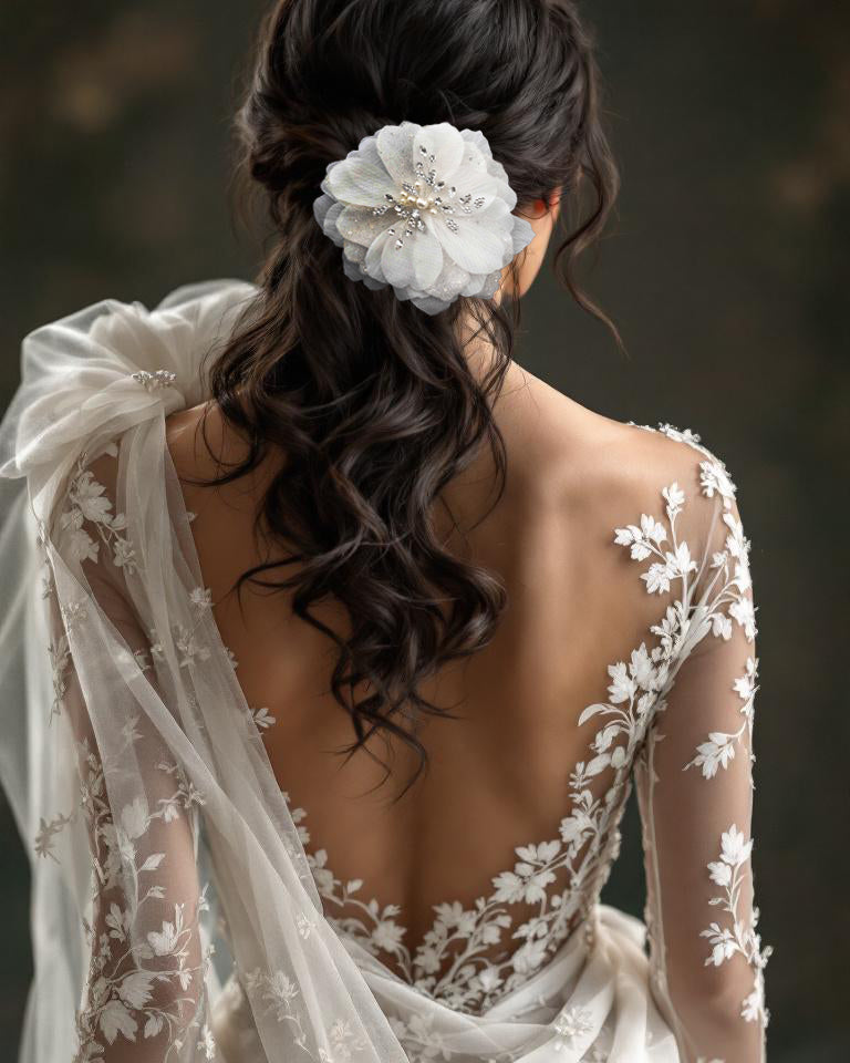 Woman wearing a wedding dress with floral details and a white flower in her hair.