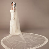 Bride wearing a long, elegant white wedding veil against a brown background Royal Cathedral Mantilla Veil with Wide Chantilly Lace