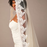Woman wearing a white wedding dress with a lace veil against a plain Royal Cathedral Mantilla Veil with Wide Chantilly Lace background