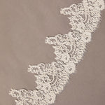 Close-up of intricate lace trim on a beige background Royal Cathedral Mantilla Veil with Wide Chantilly Lace