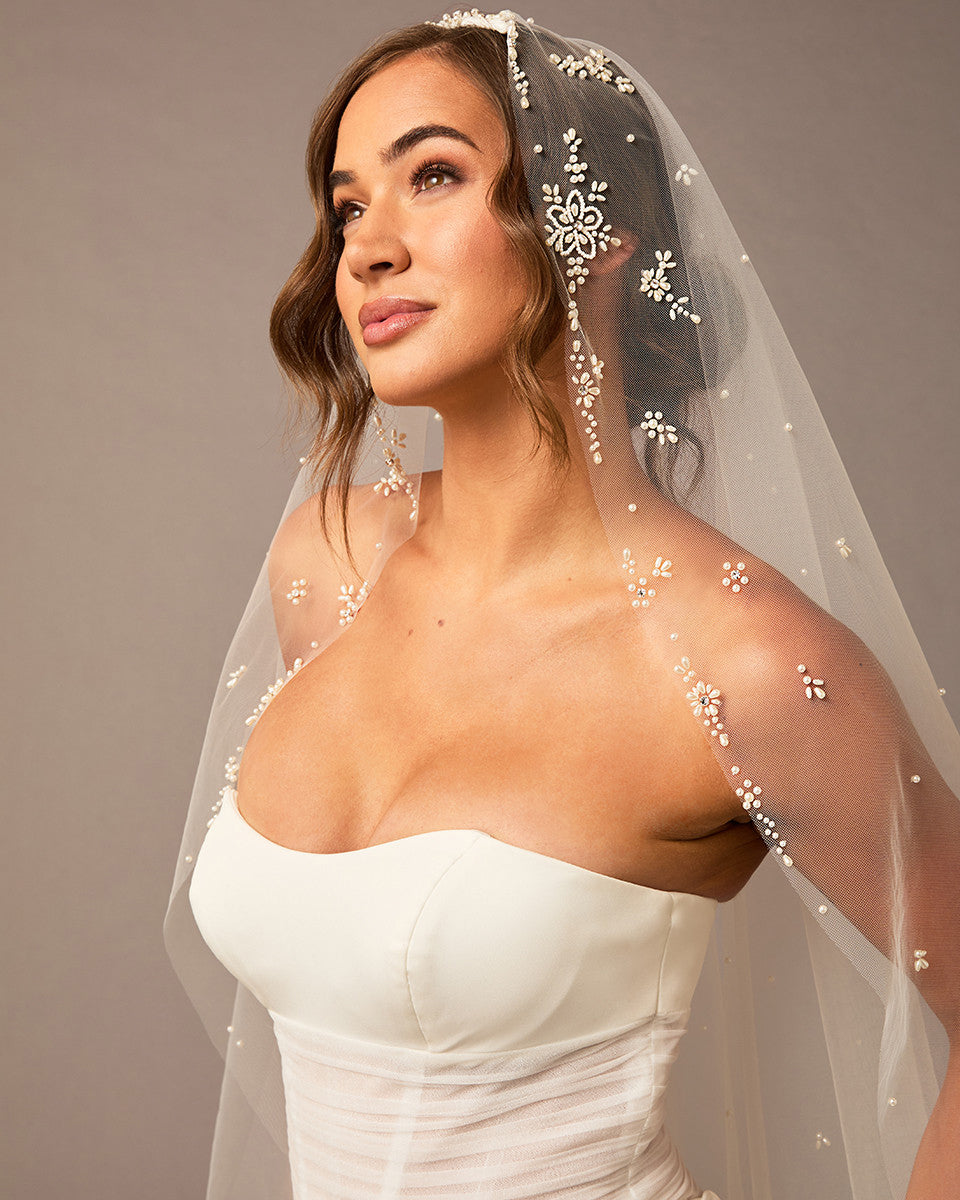 Fingertip Mantilla Veil with Pearl Clusters and Scatter Woman wearing a wedding dress with a decorative veil against a neutral background