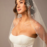 Fingertip Mantilla Veil with Pearl Clusters and Scatter Woman wearing a wedding dress with a decorative veil against a neutral background