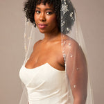 Royal Mantilla Veil with Pearl Clusters and Scatter Woman wearing a wedding dress with a veil against a neutral background