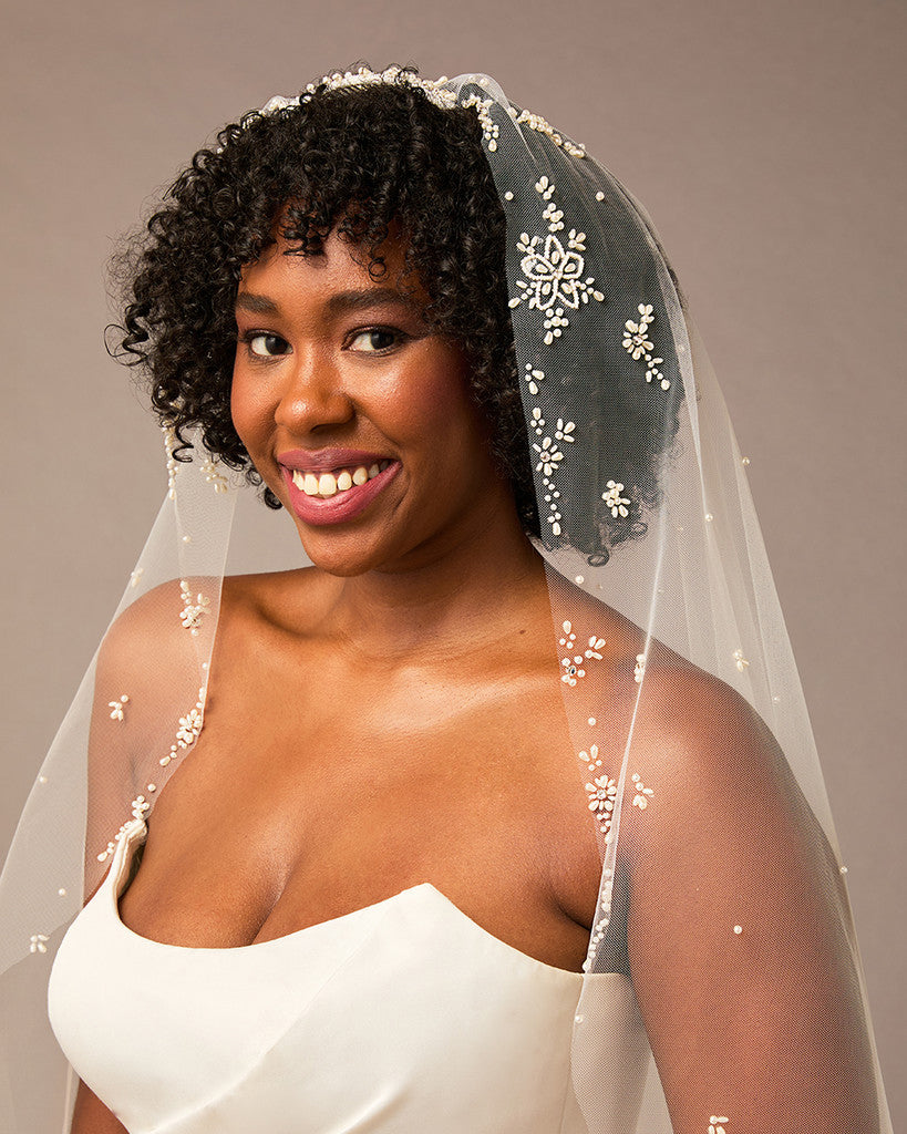 Royal Mantilla Veil with Pearl Clusters and Scatter Woman wearing a  wedding dress and veil with floral details against a neutral background