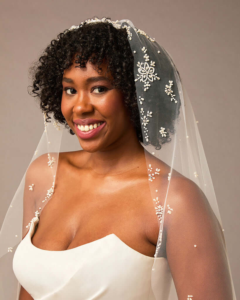 Royal Mantilla Veil with Pearl Clusters and Scatter Woman wearing a  wedding dress and veil with floral details against a neutral background