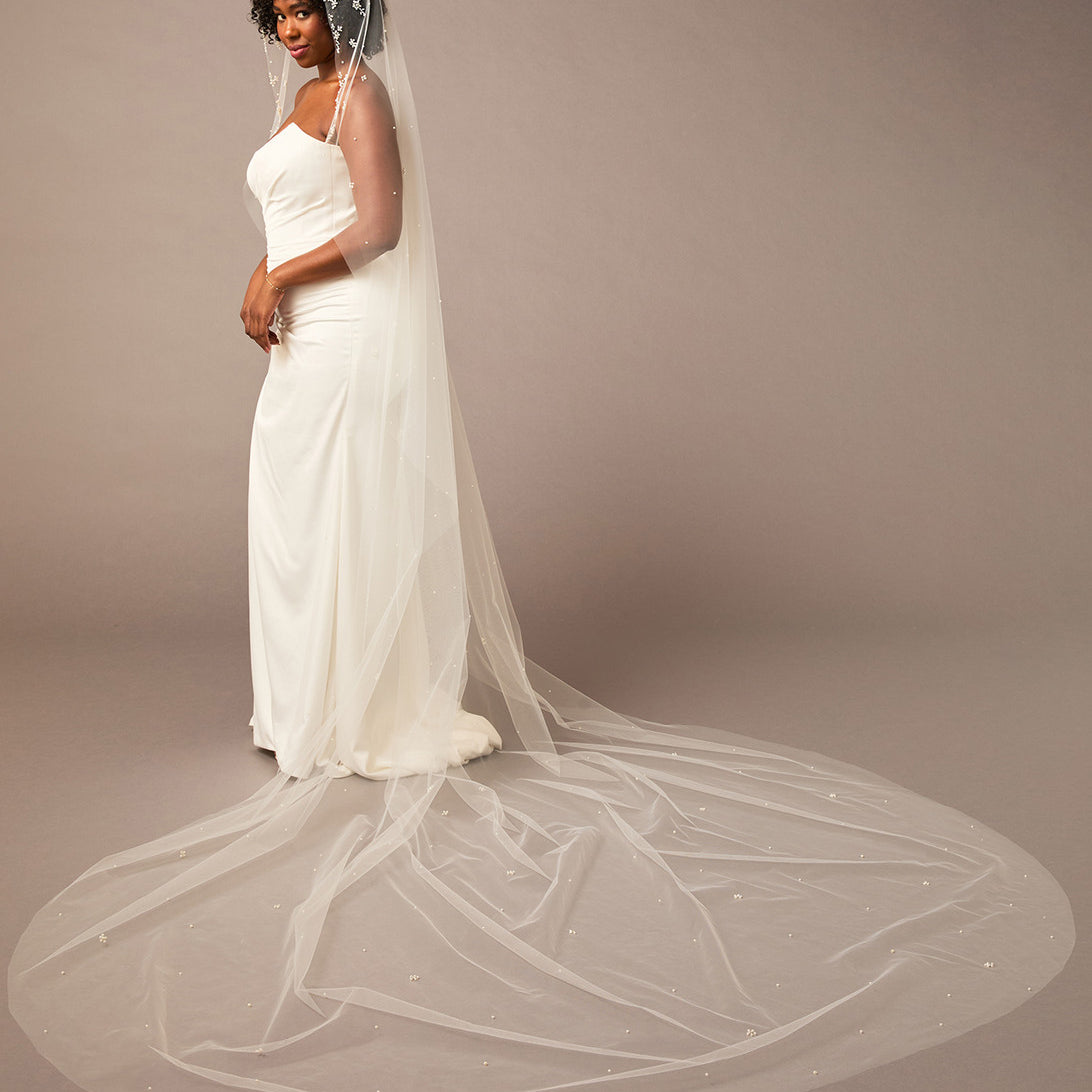 Royal Mantilla Veil with Pearl Clusters and Scatter Woman wearing a wedding dress with a long veil on a plain background
