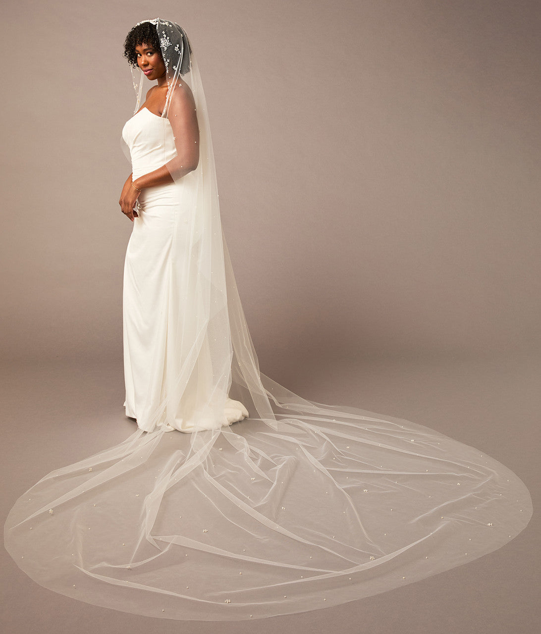 Royal Mantilla Veil with Pearl Clusters and Scatter Woman wearing a wedding dress with a long veil on a plain background