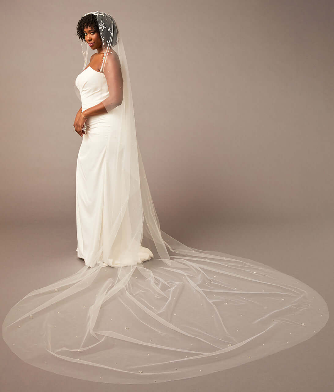 Royal Mantilla Veil with Pearl Clusters and Scatter Woman wearing a wedding dress with a long veil on a plain background