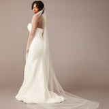 Cathedral Veil with Scattered Dense Pearl Clusters Woman wearing a wedding dress with a long veil against a brown background