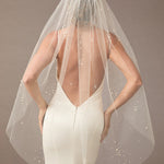 Fingertip Veil with Scattered Dense Pearl Clusters wedding dress with a sheer veil on a plain background