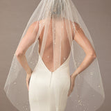 Fingertip Veil with Scattered Dense Pearl Clusters wedding dress with a sheer veil on a plain background