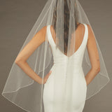 Fingertip Veil with Pearls and Sequins Bride wearing a  wedding dress with a sheer veil against a brown background