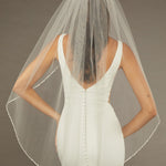 Metal Flower and Beads Fingertip Bridal Veil Bride wearing a  wedding dress with a sheer veil against a neutral background