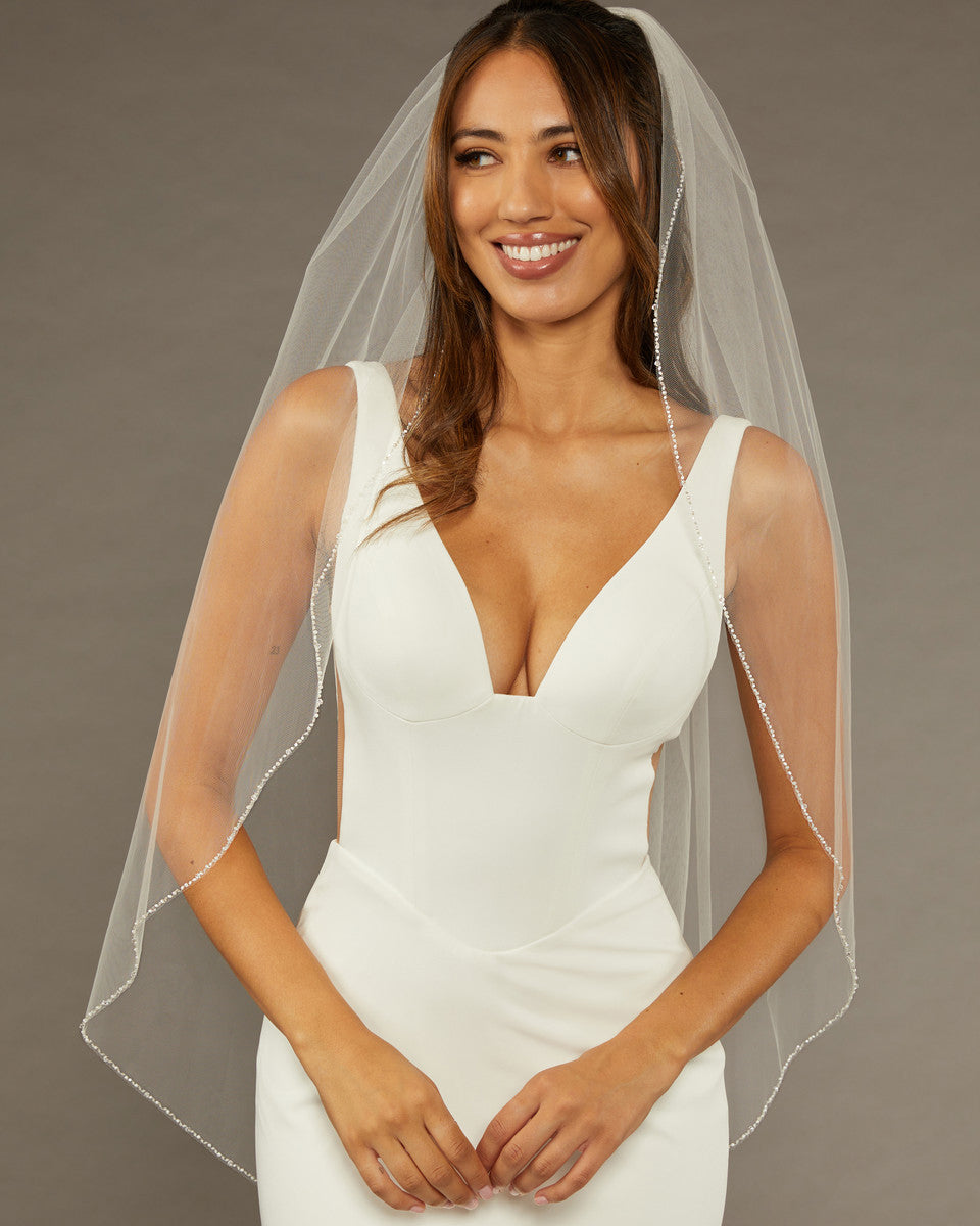 Bridal Veil with Crystal Beads and Pearls Woman wearing a wedding dress with a veil against a neutral background