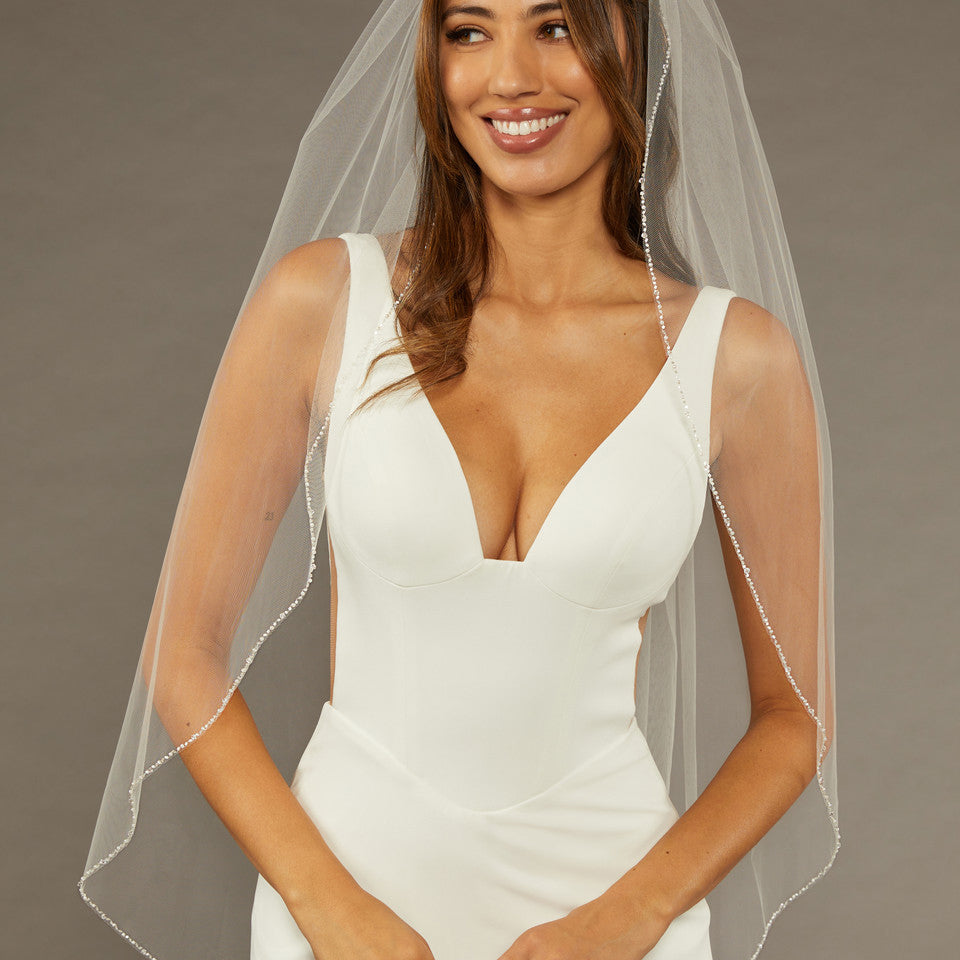 Bridal Veil with Crystal Beads and Pearls Woman wearing a wedding dress with a veil against a neutral background