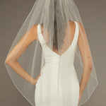 Bridal Veil with Crystal Beads and Pearls Woman wearing a wedding dress with a sheer veil against a brown background