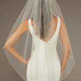 Bridal Veil with Crystal Beads and Pearls Woman wearing a wedding dress with a sheer veil against a brown background