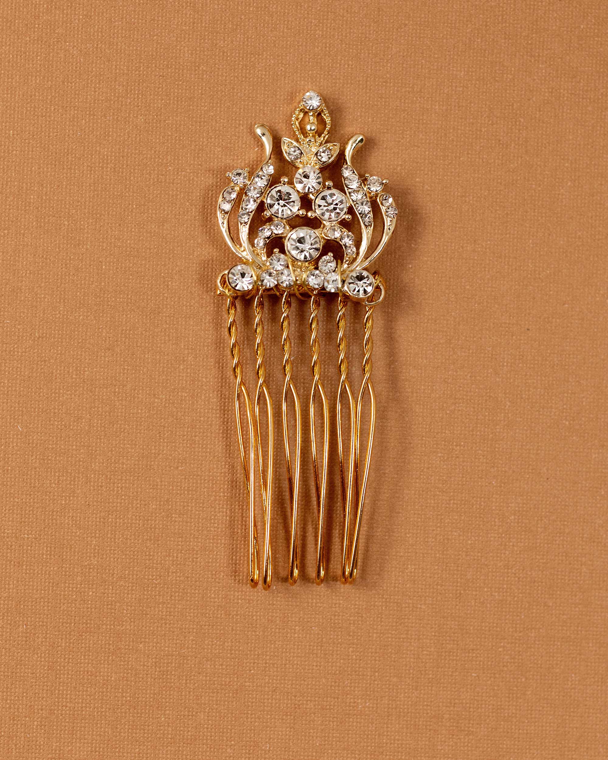 Regal Styled Small Wedding Hair Comb Gold-plated hair comb with clear rhinestones on a textured tan background.