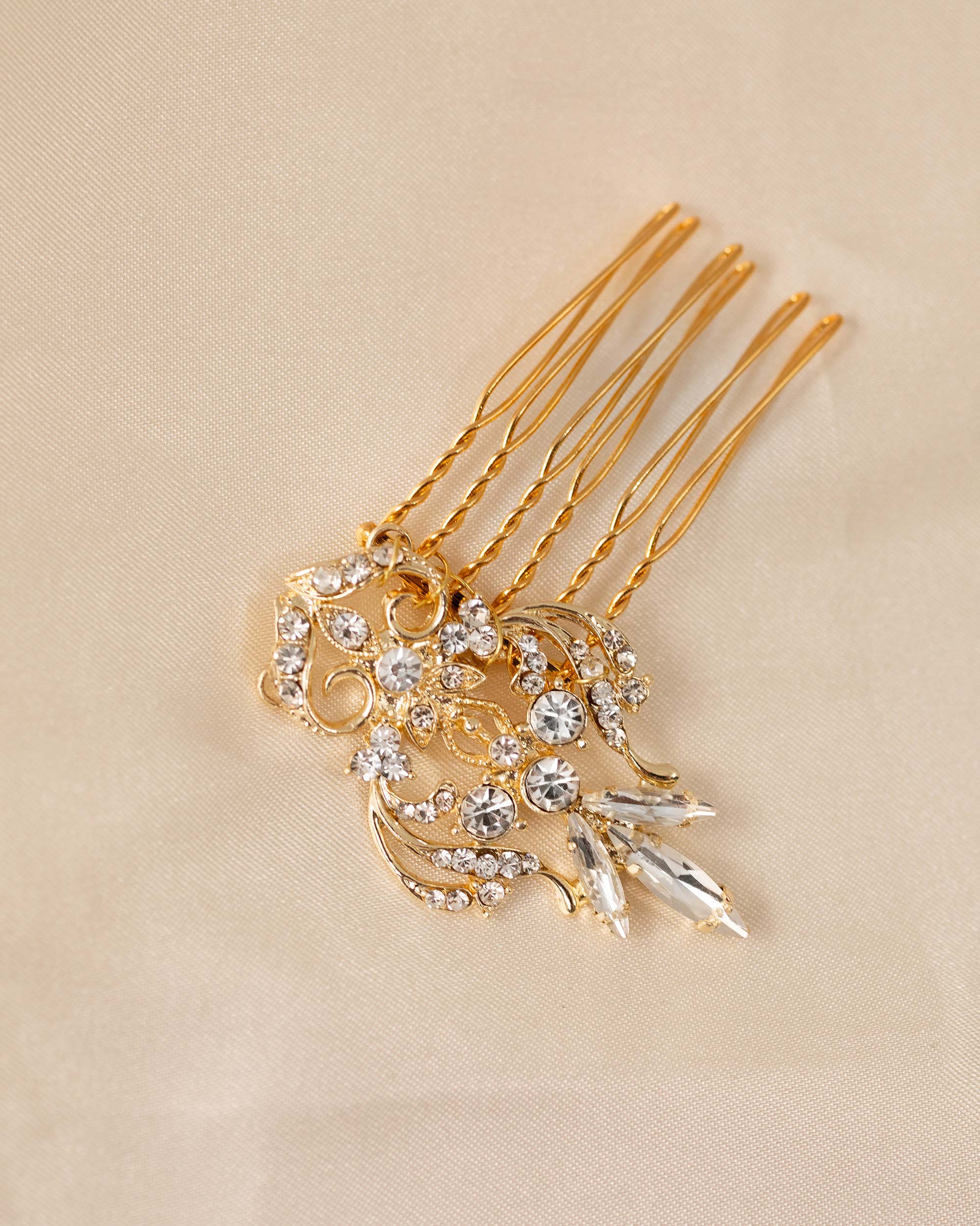 Dainty Regal Wedding Hair Comb gold hair comb decorated with clear rhinestones displayed on a beige fabric background.