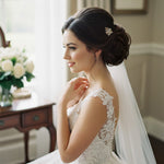 a bride in an ivory dress and veil with a small gold comb in her hair