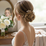looking at the back of a bride with a blonde updo wearing a small intricate gold wedding hair comb.