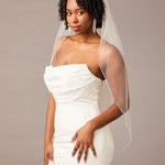 Fingertip Bridal Veil with Rhinestone Chain Trim Woman wearing a  strapless dress with a sheer veil against a plain background