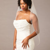 Fingertip Bridal Veil with Rhinestone Chain Trim Woman wearing a  strapless dress with a sheer veil against a plain background